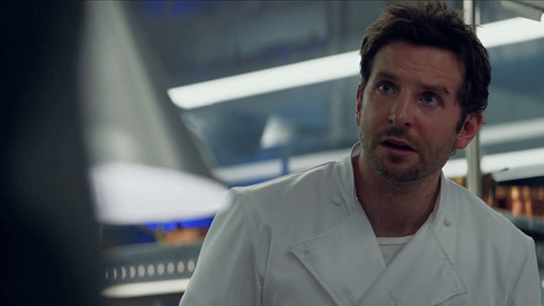 Bradley Cooper as Adam Jones chef stood in a professional kitchen looking worried in Burnt movie 2015