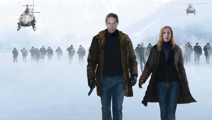 Mulder and Scully walking in the snow with an army and two helicopters behind them