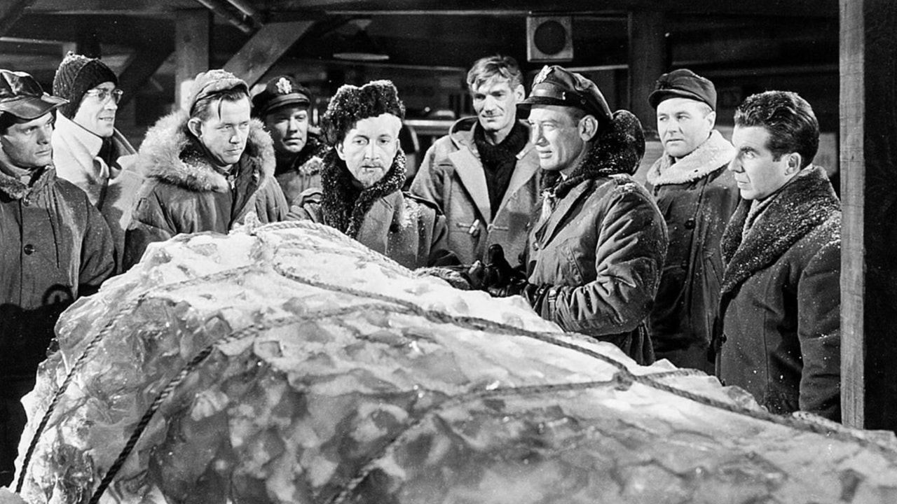9 people surround a block of frozen ice in 1951 film The Thing From Another World